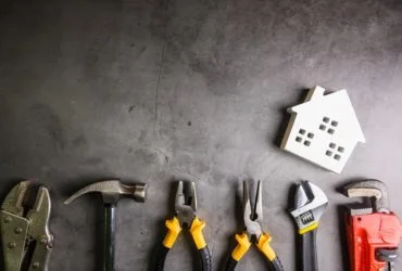 Wooden house and construction tools on stone pattern background with copy space.Home Repair concept, Repair maintenance concept, Renovation concept.