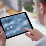 Smart home control on tablet. Interior of living room in the background.